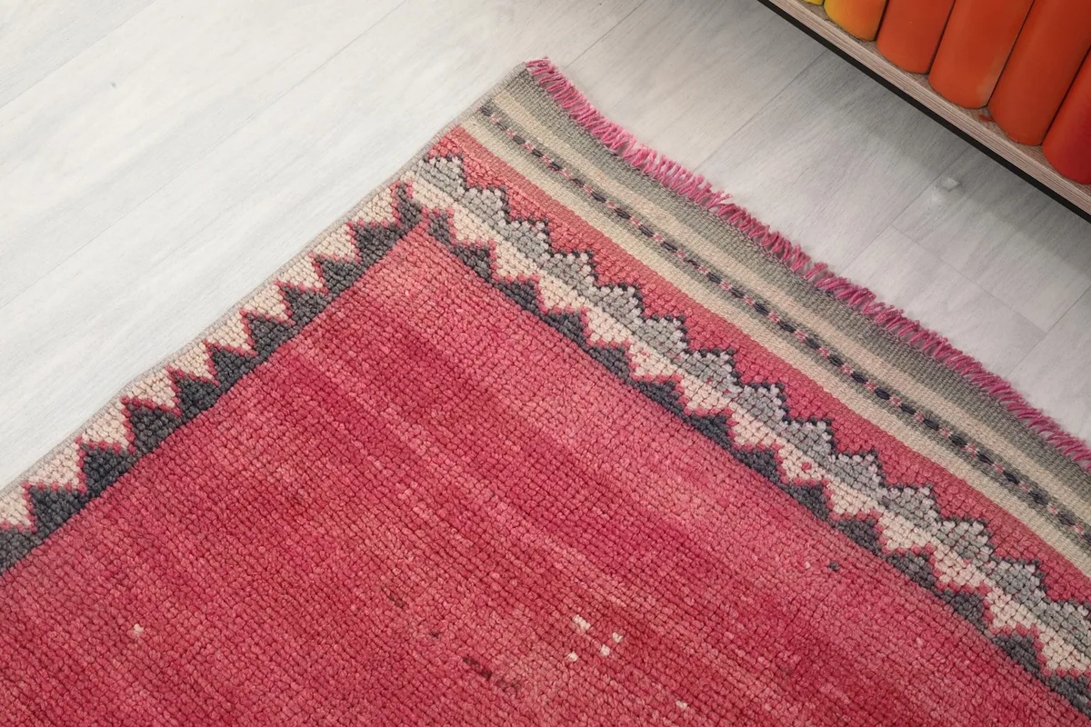 Close-up of the intricate charcoal and beige zigzag border design at the corner of the rose runner.