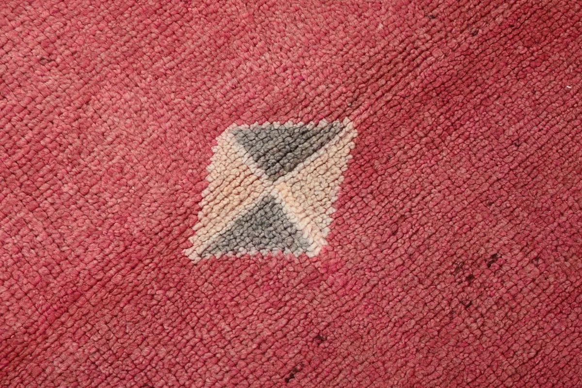 Extreme close-up of the low wool pile, showing the hand-knotted texture and color variation in the rose field.