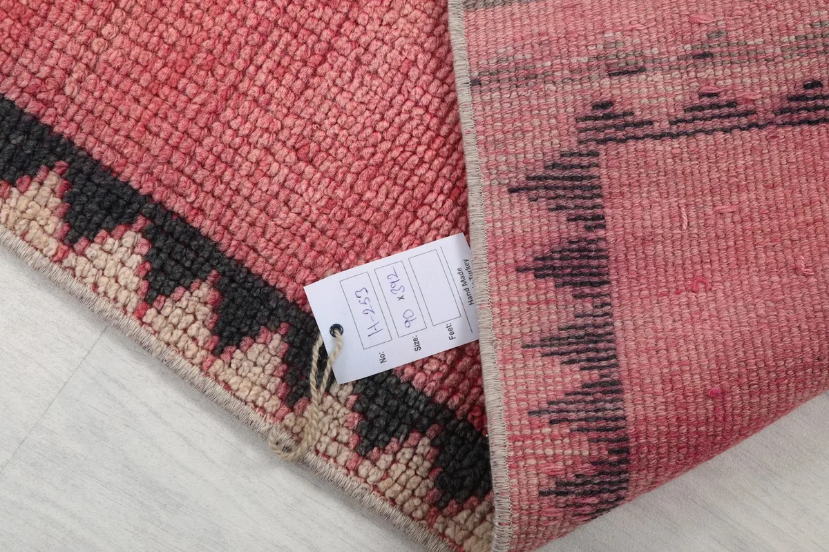 Corner of the rug with a tag, showing the hand-knotted construction and the quality of the vintage piece.