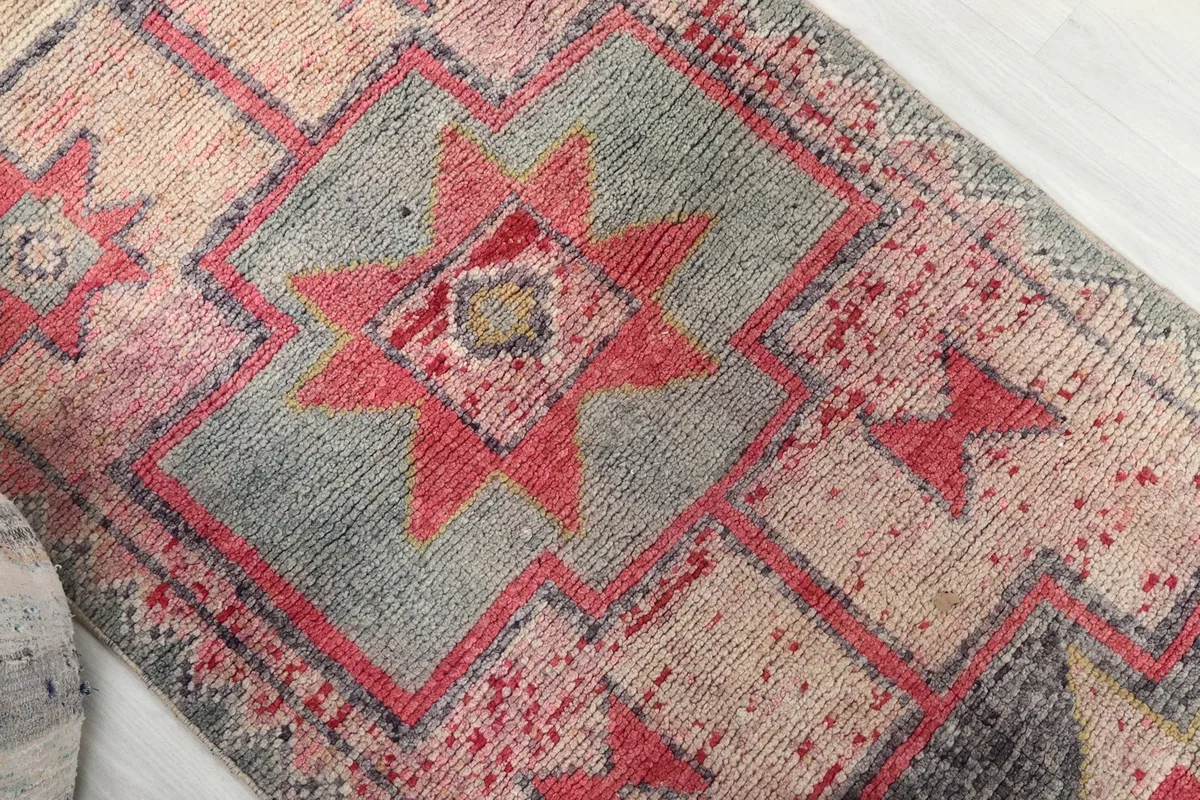 Close-up detail of a central rose and gray geometric star motif on the beige runner rug