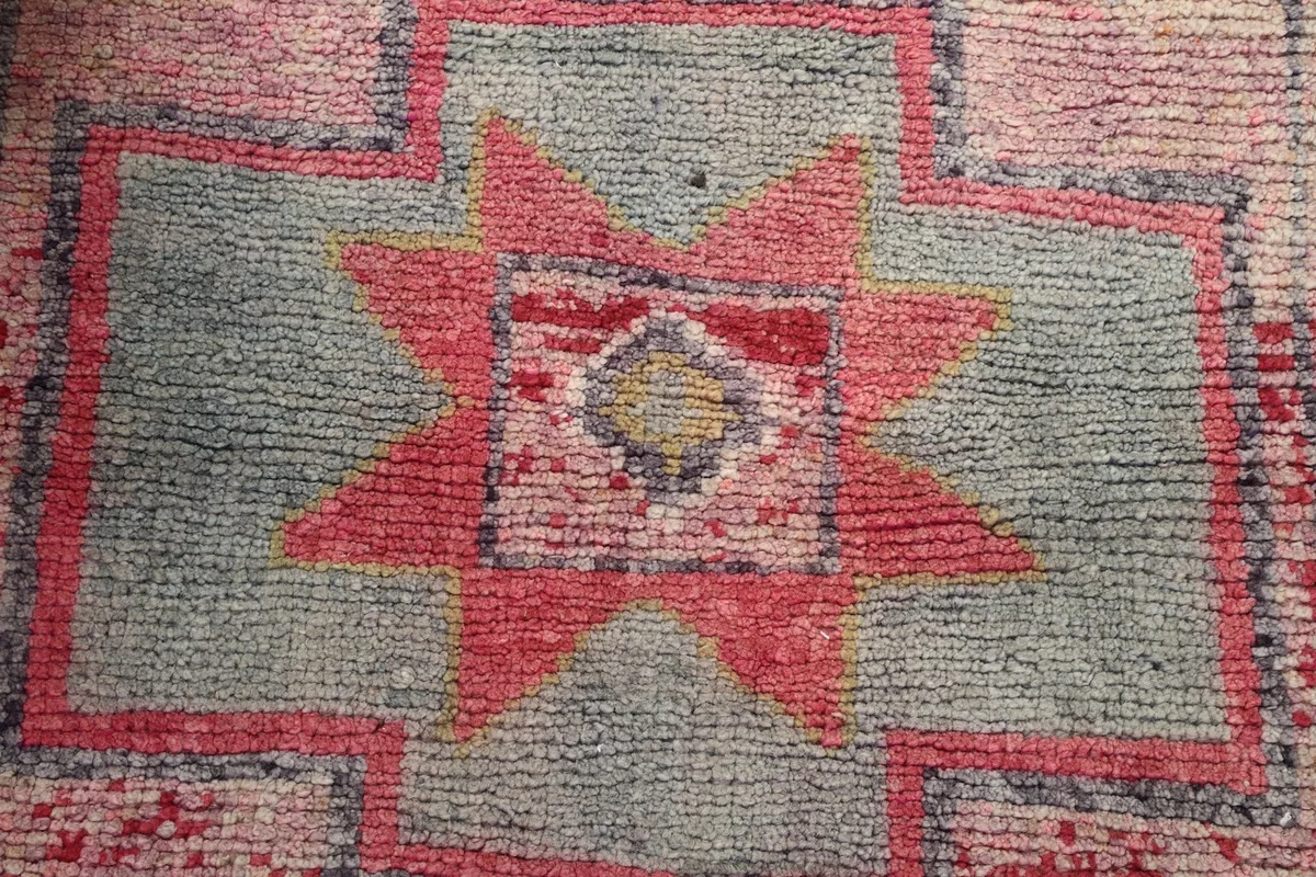 Detailed view of the hand-knotted pile and colors within a rose and gray motif on the runner rug