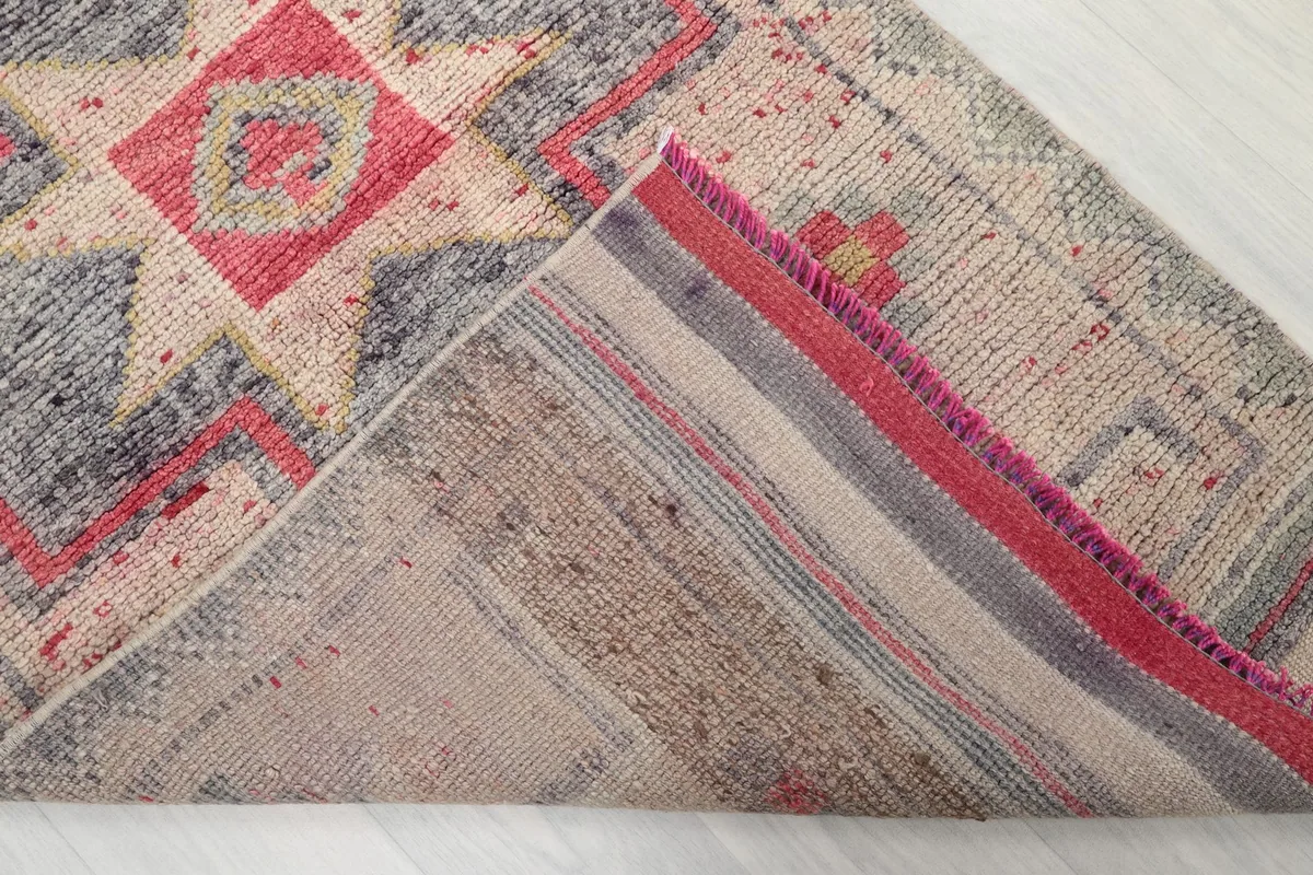 Corner of the runner rug folded to show the cotton foundation and tight hand-knotting from the back