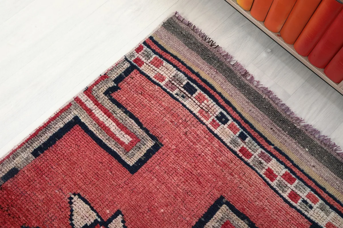 Detail of the rug's border and fringe, with colors including red, gray, and navy