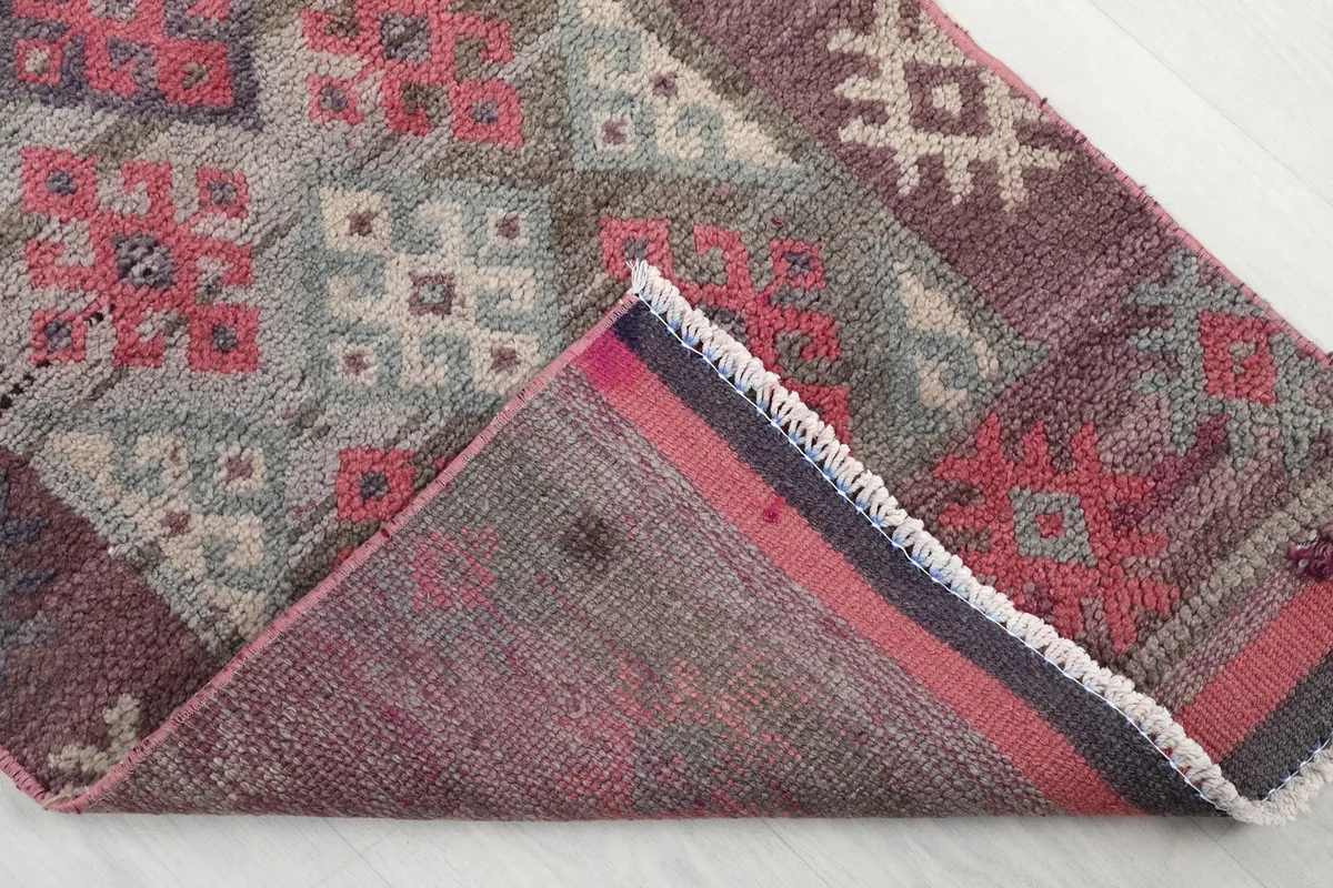 Folded corner of the rug revealing the cotton foundation and the reverse side of the hand-knotted construction.