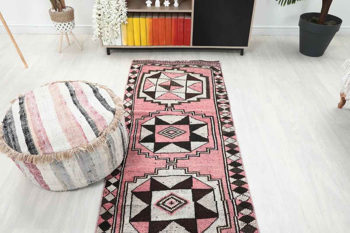 Overhead view of the pink runner rug in a room, next to a striped ottoman