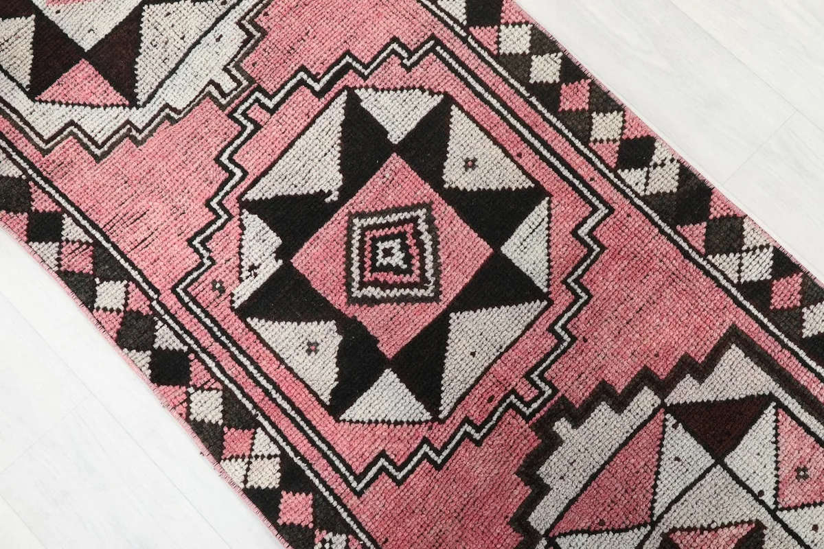 Close-up of the center geometric medallion with pink, black, and cream colors