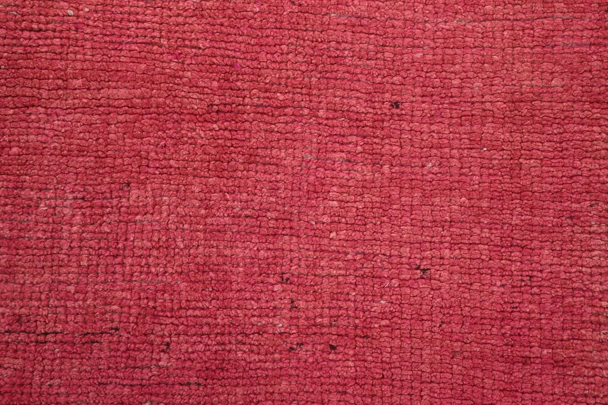 Close-up texture of the rose wool pile, showing the hand-knotted weave and low pile height.