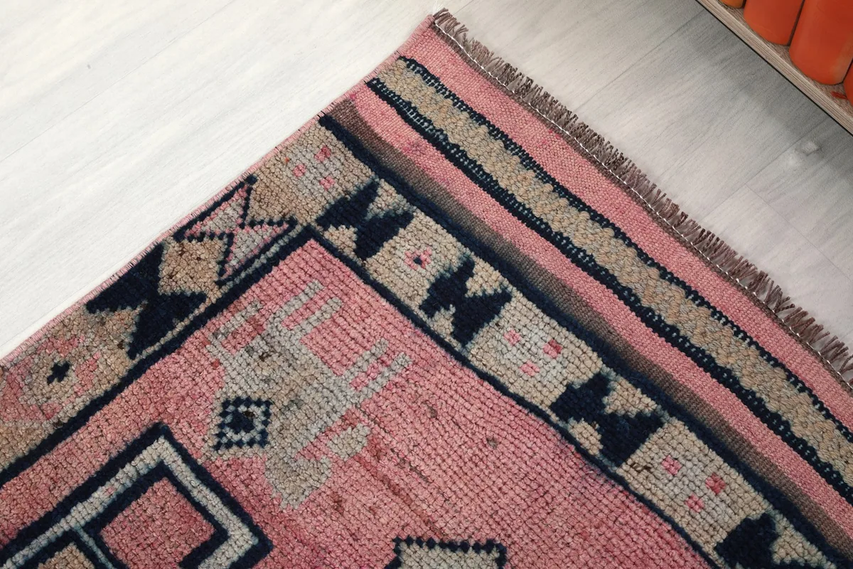 Close-up of the side border of the rug, featuring navy tribal symbols on a beige strip