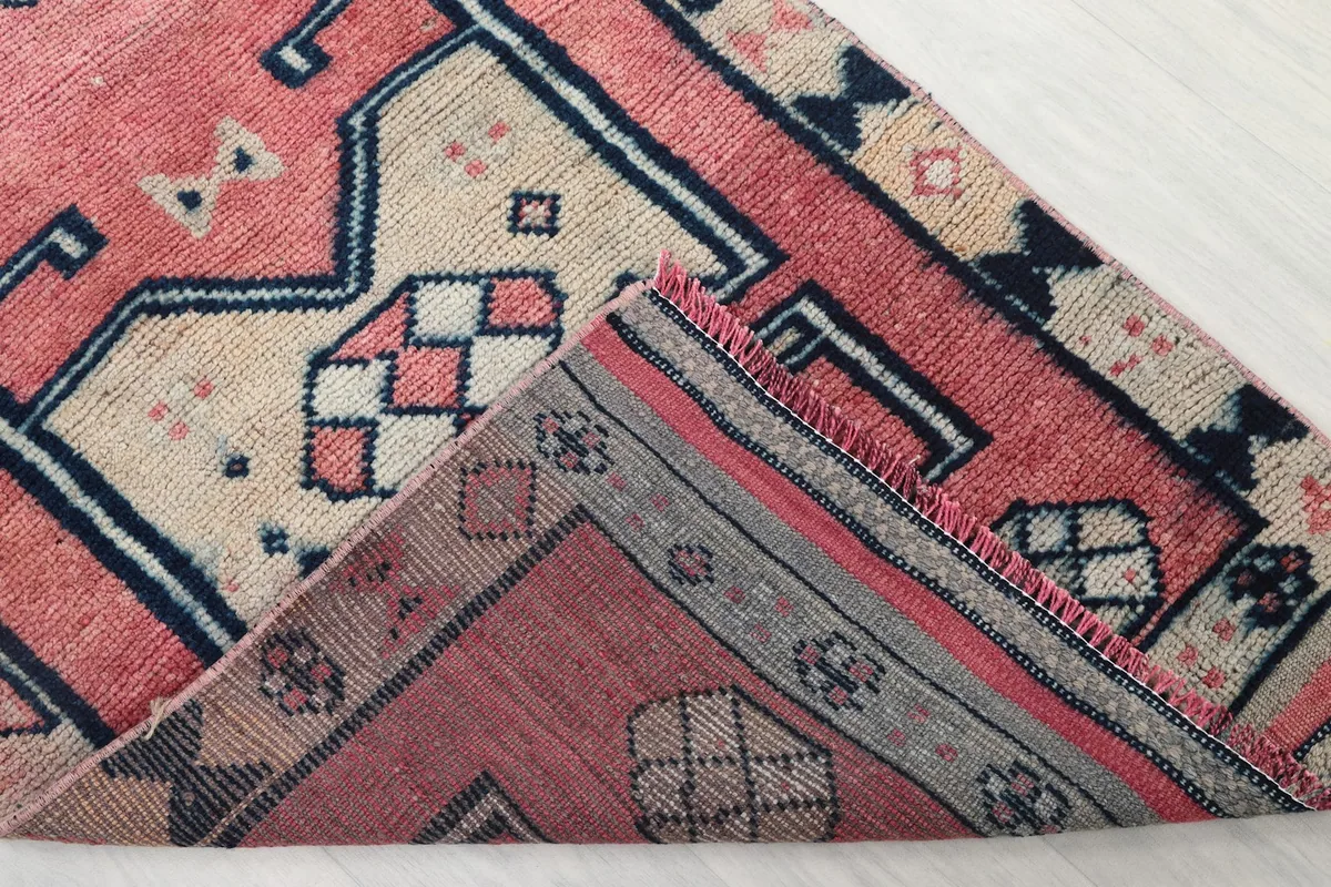 Folded corner of the rug revealing the cotton foundation and the reverse side of the pattern
