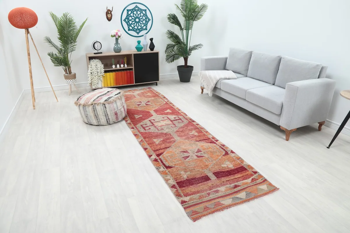 Angled view of the rust and red runner rug in a bright room with furniture