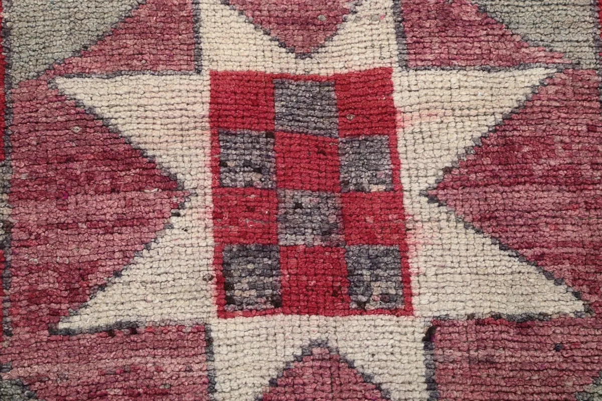Extreme close-up of the low wool pile and hand-knotted texture within a star motif
