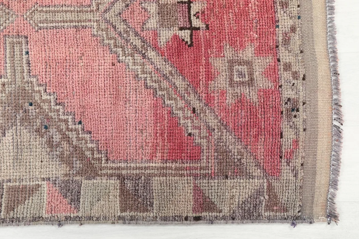 Close-up detail of the lower end of the rug, highlighting the rose field and gray geometric border patterns.