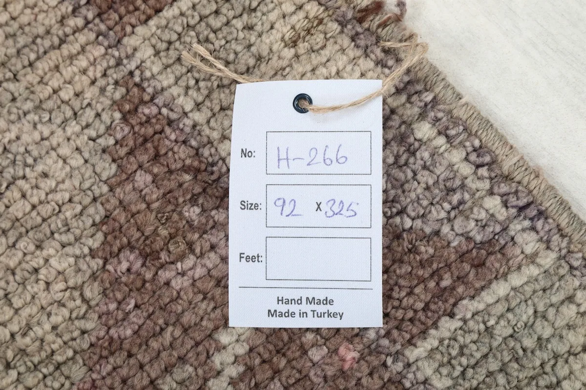 Close-up of the rug's label, showing the hand-made origin and dimensions in centimeters.