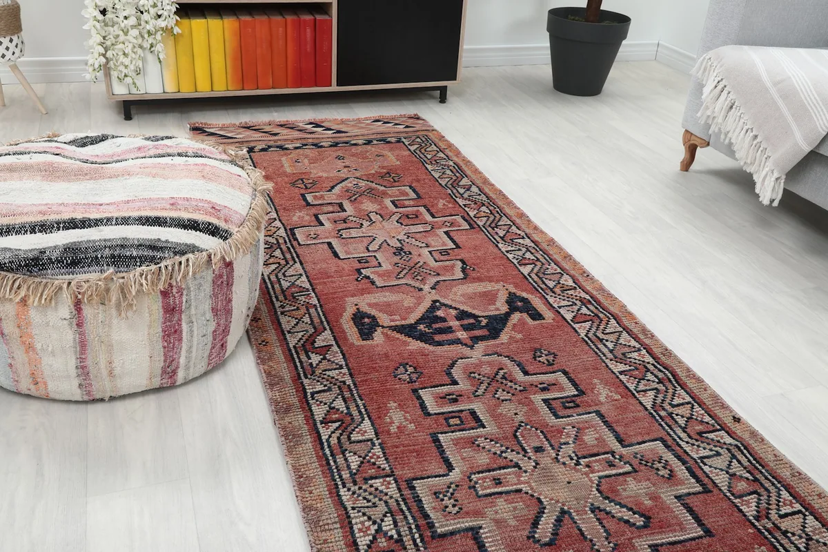 Close-up view of the vintage rust runner rug in a room setting, showing its texture and colors