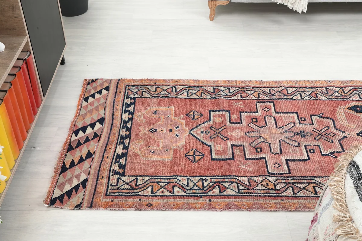View of the rust runner rug from one end in a room, showing its length and design