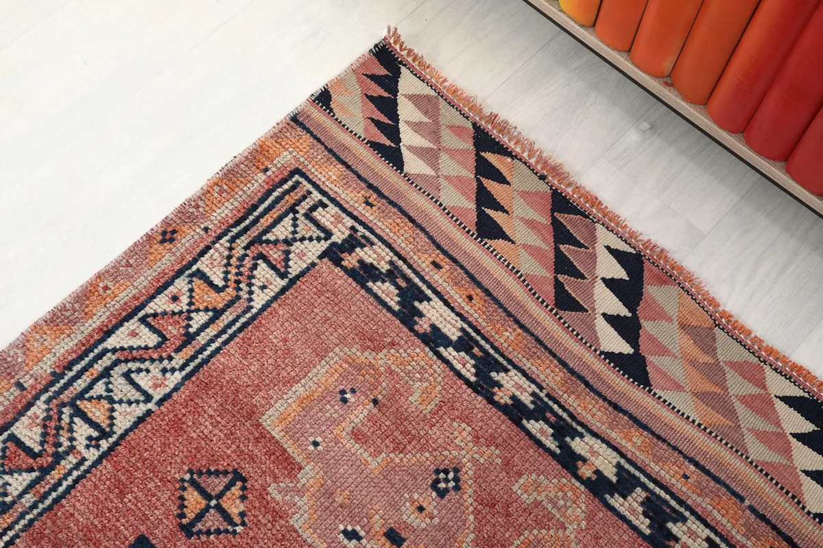 Corner detail of the rust runner rug, showcasing the intricate border and end patterns