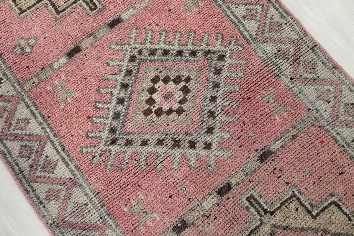 Close-up on a central geometric medallion motif in beige, gray, and brown on the rose field