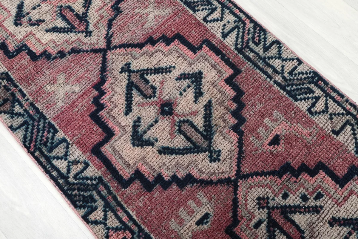 Close-up of a central geometric motif in navy and beige against the rose field