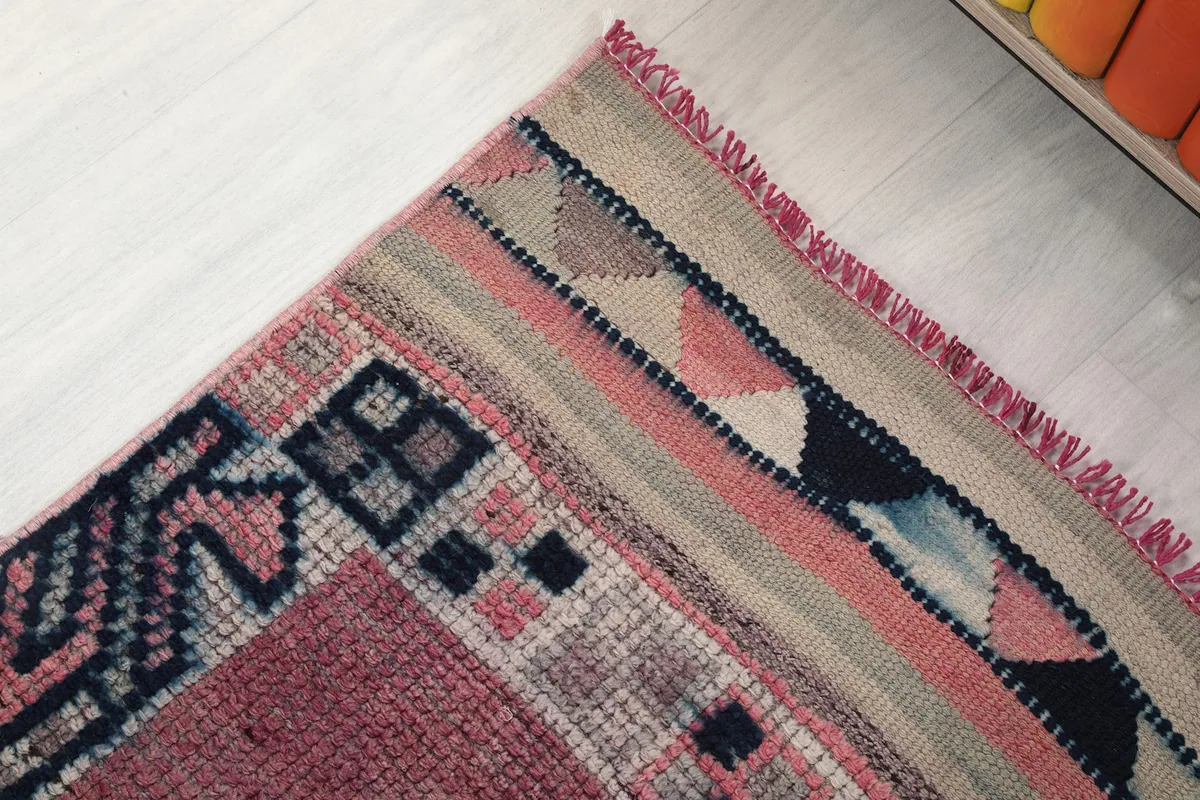 Detail of the rug's end border, showcasing the striped patterns and fringe