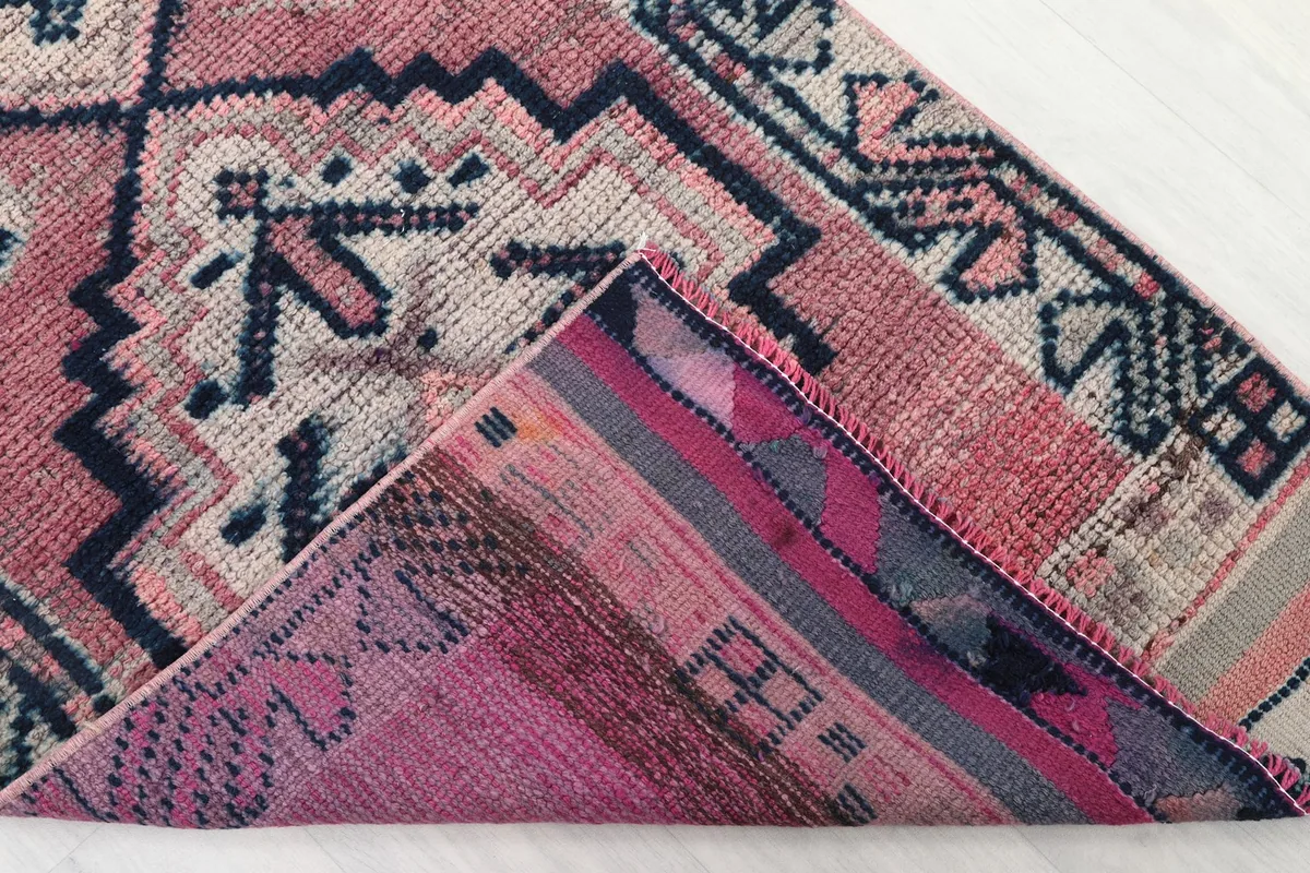 Corner of the rug folded to reveal the backside, showing the hand-knotted foundation