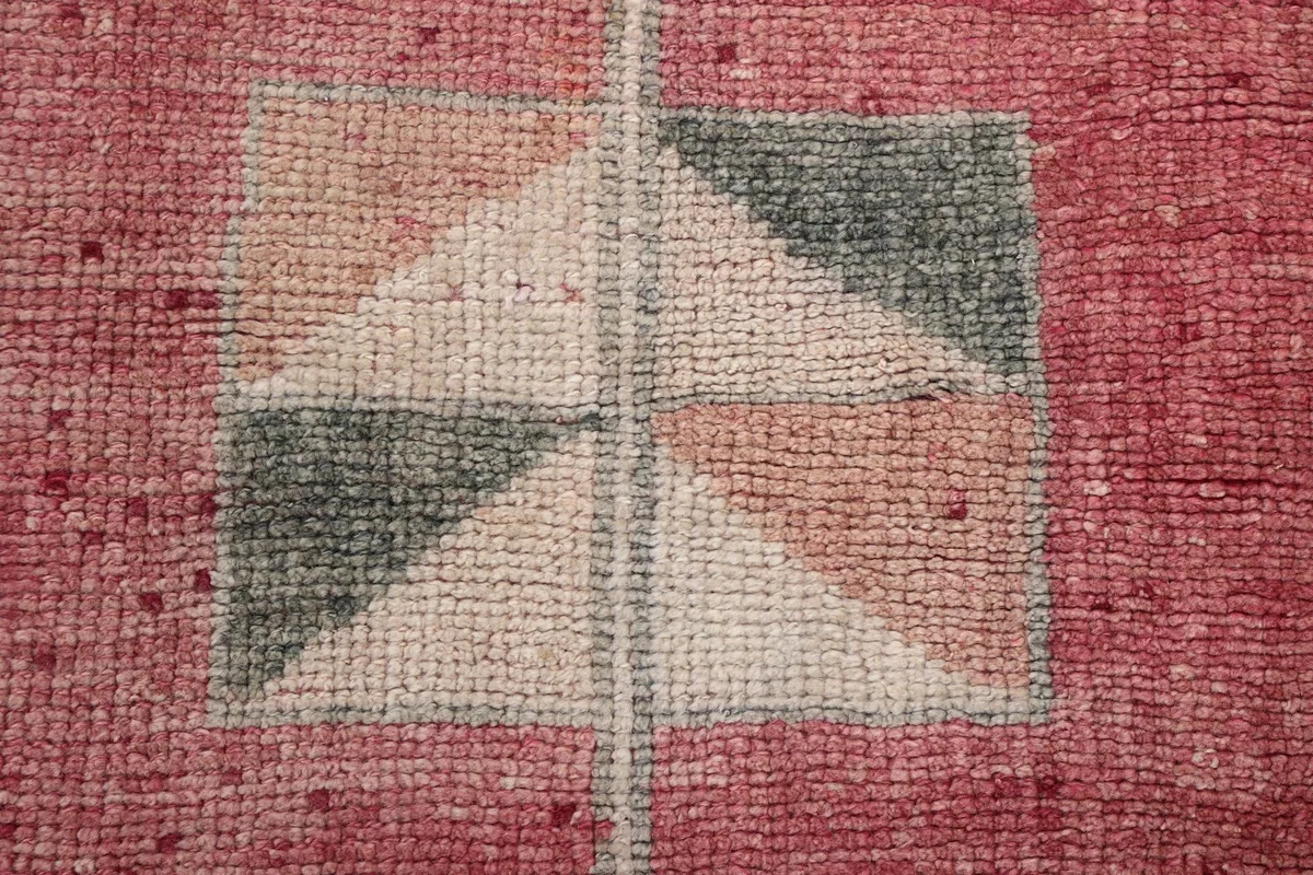 Close-up of a central geometric motif, revealing the hand-knotted wool pile texture.