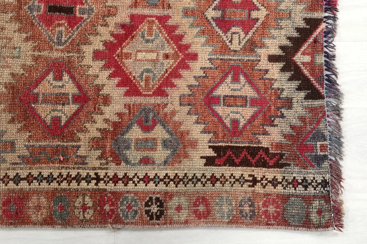 Detailed view of the rug's end, showing geometric patterns and border design