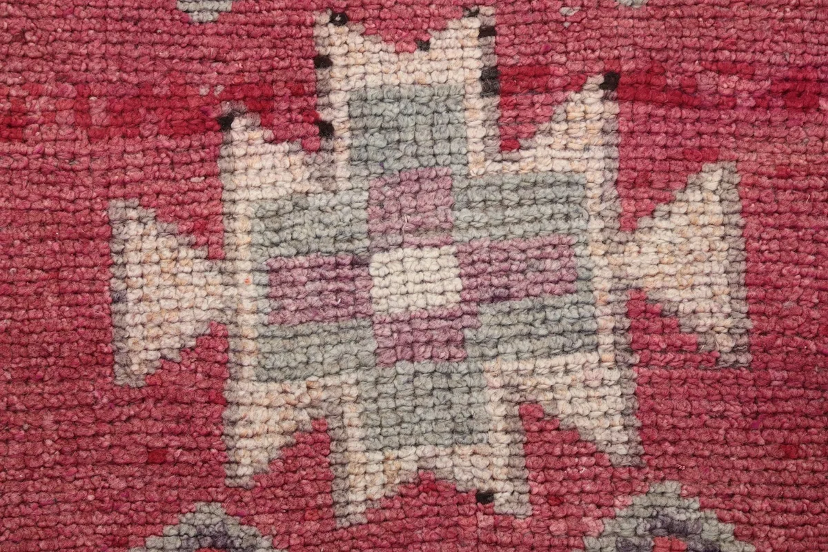 Extreme close-up of a central geometric motif with rose, beige, gray, and purple tones