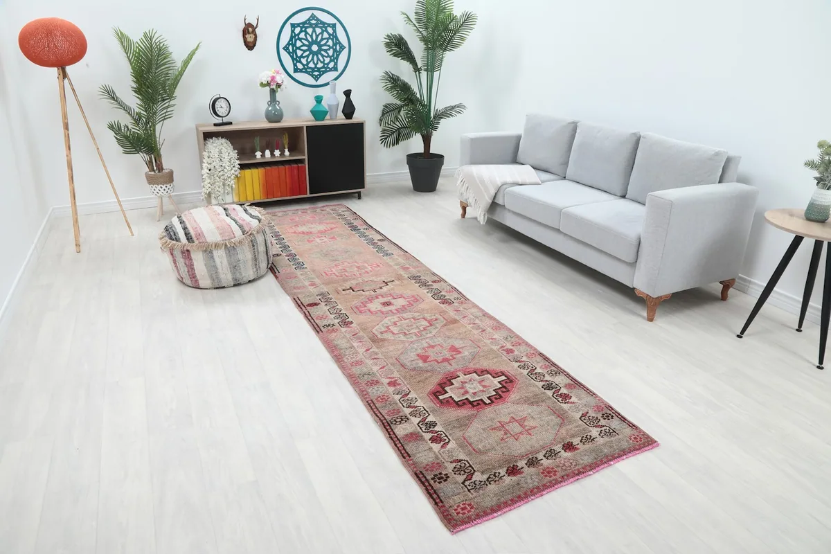 Runner rug viewed from an angle in a room, highlighting its beige field and rose geometric patterns.