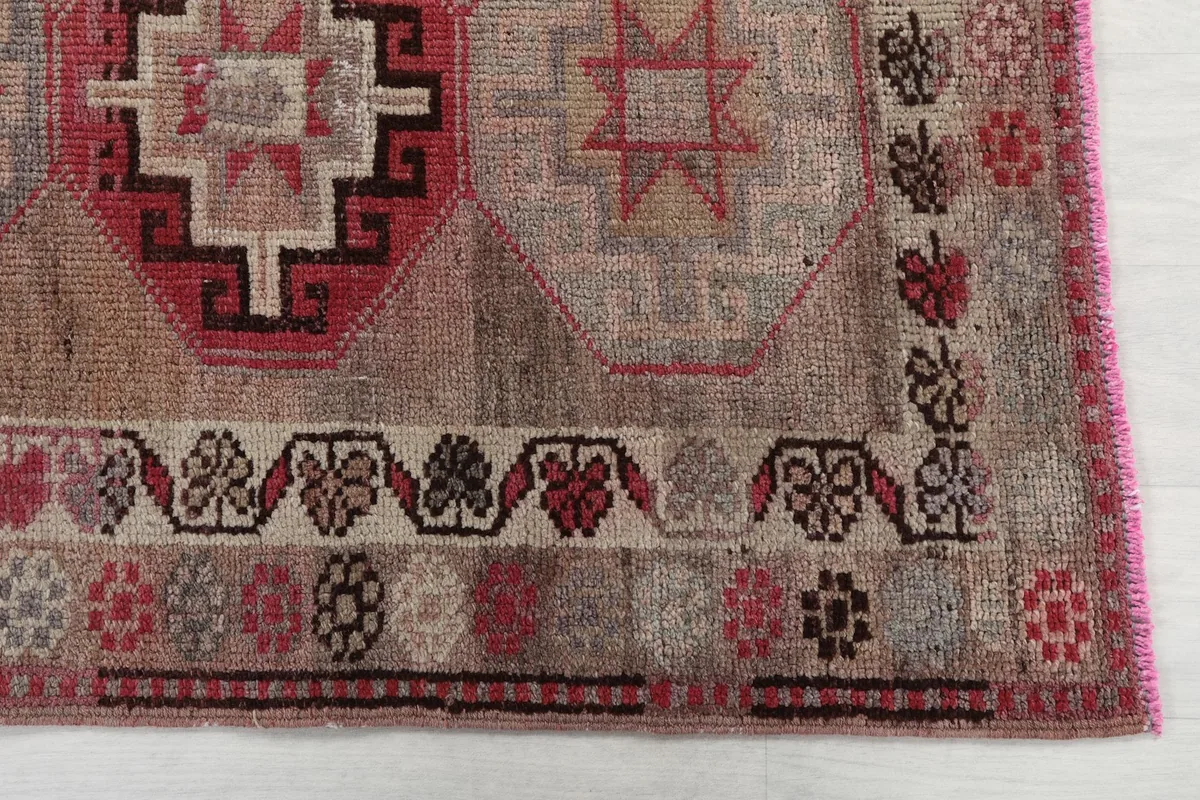 Detailed view of the rug's end, showing the border design and part of a rose and gray medallion.