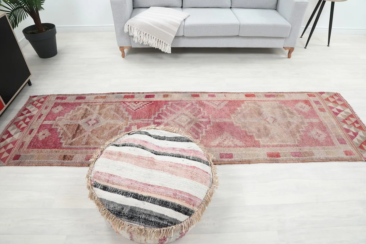 Full room shot with the runner rug, a sofa, and a pouf, illustrating scale and decor style