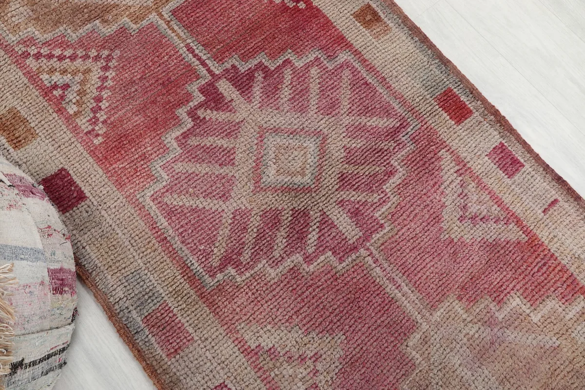Detailed view of the central geometric motif in rose and tan, with visible pile texture
