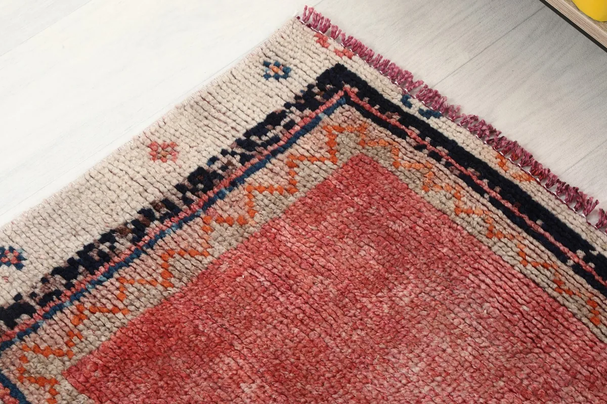 Corner detail of the rug's beige border, showcasing the navy and rust tribal motifs.
