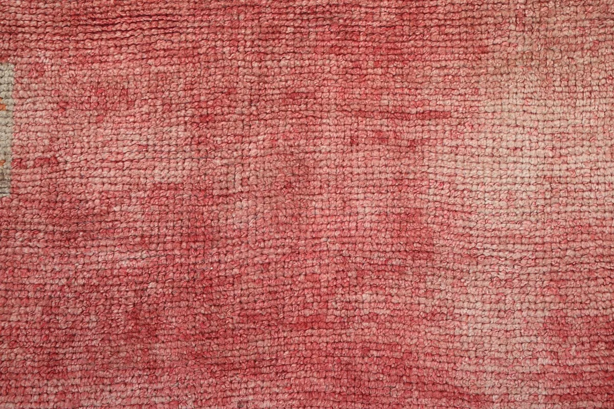 Close-up of the low pile and hand-knotted texture of the vintage rose wool rug.