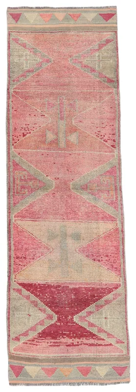 Full overhead view of a rose and gray geometric Anatolian runner rug on a white background