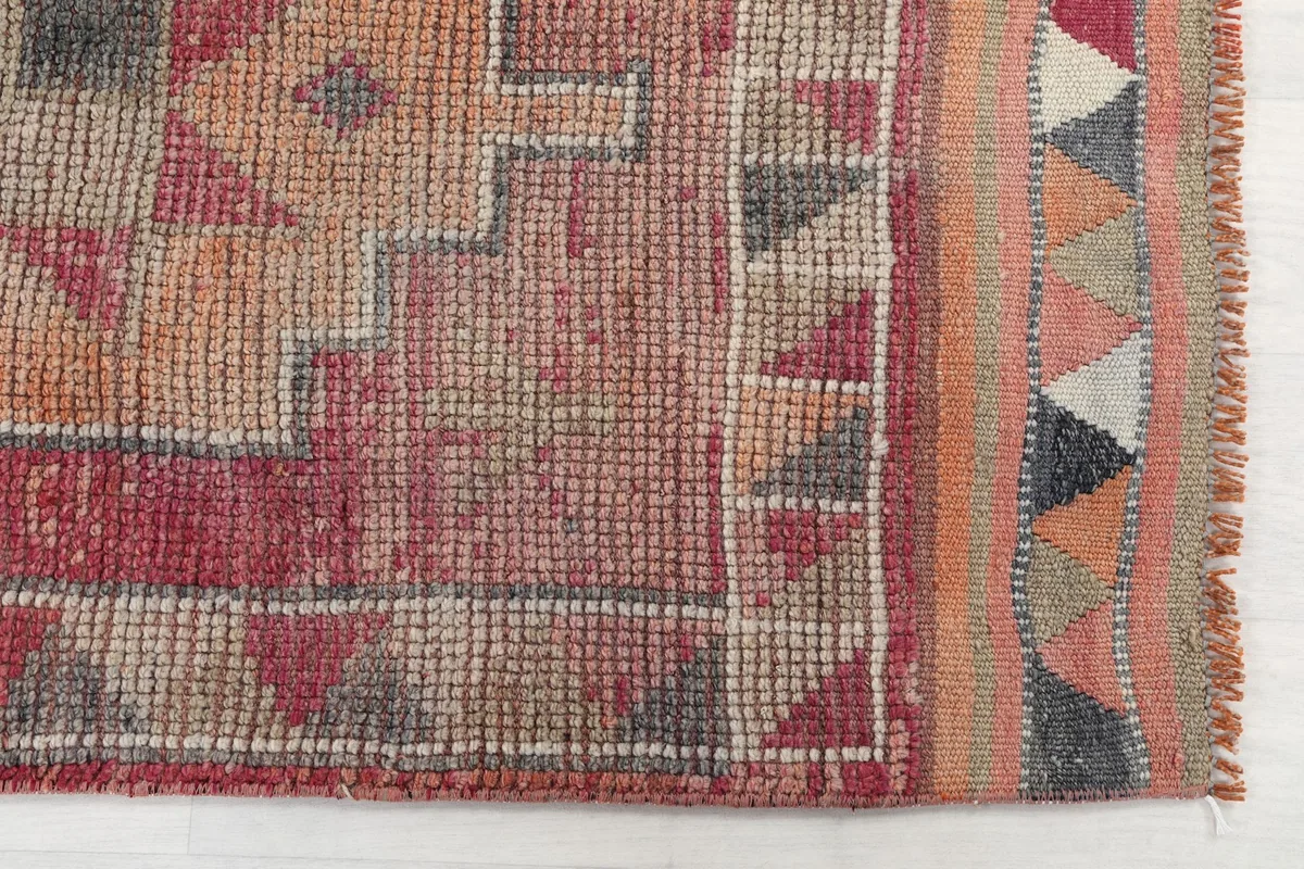 Detailed view of the hand-knotted texture and border design with small triangles.