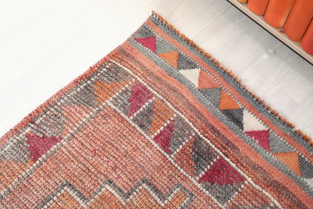 Corner detail of the rug's border, showcasing the varied colors and triangular patterns.