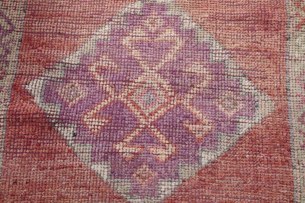 Detailed shot of the hand-knotted texture and intricate purple and tan patterns on the rug