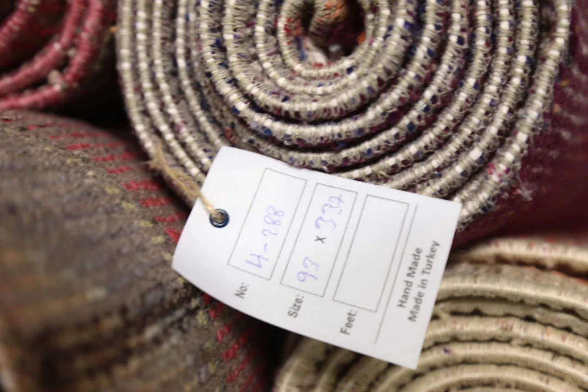 Tag displaying the size 93 x 337 cm and 'Hand Made in Turkey' on a rolled rug