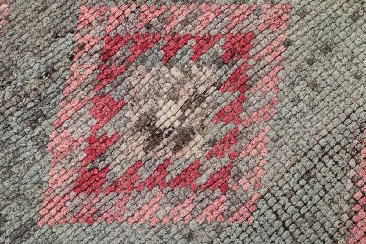 Texture detail of the hand-knotted wool pile, showing the varied rose and gray threads