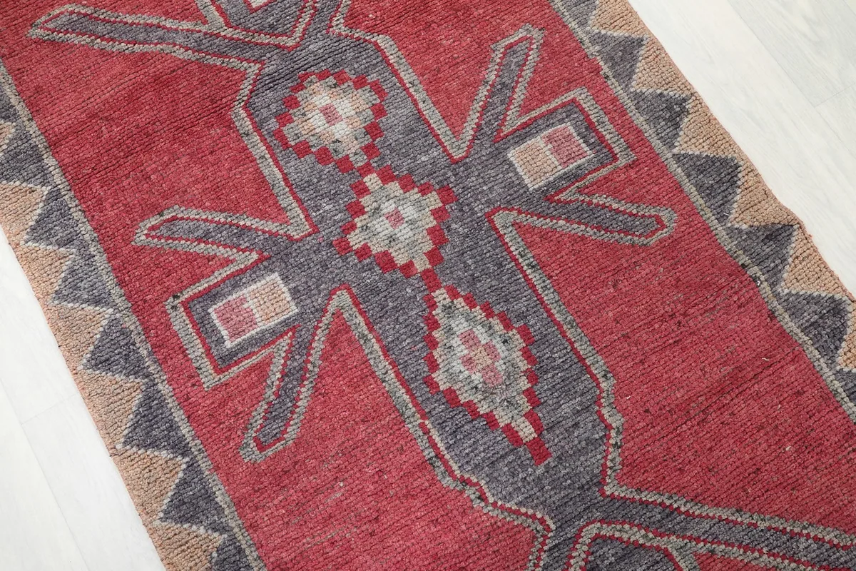 Close-up of the central tribal figure motif in gray and tan against the red field