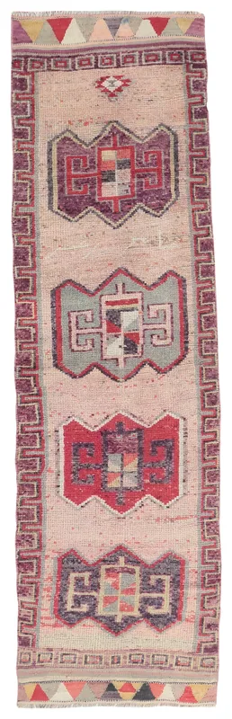 Full overhead view of a beige runner rug with red and purple geometric motifs