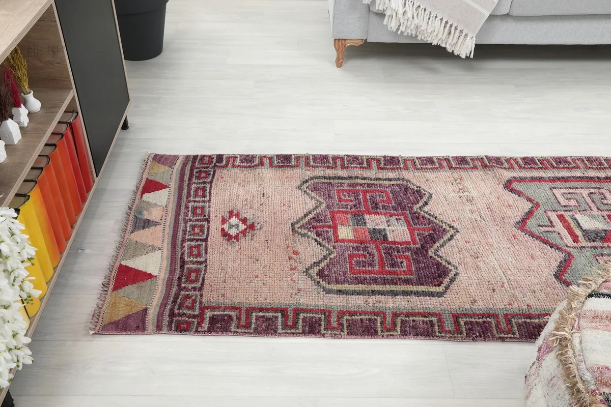 Runner rug extending from a cabinet towards a sofa in a bright room
