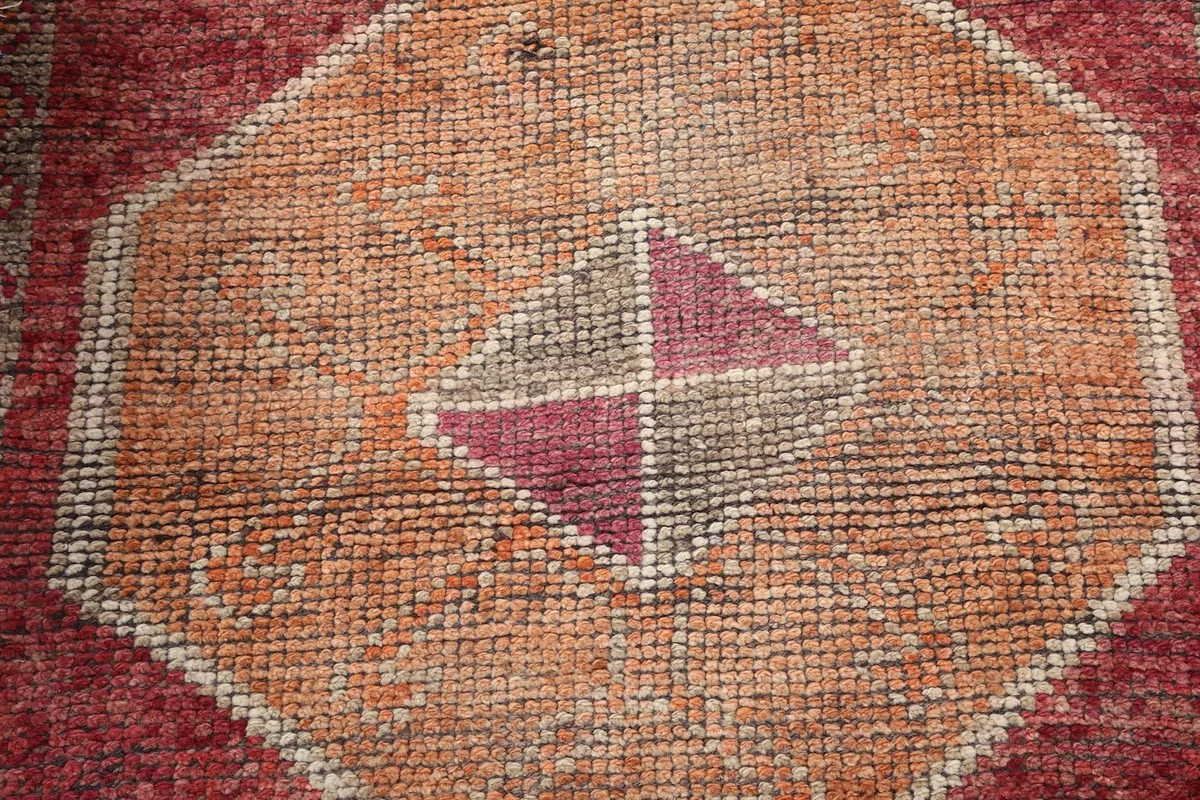 Close-up of the low wool pile texture and faded colors of a geometric motif