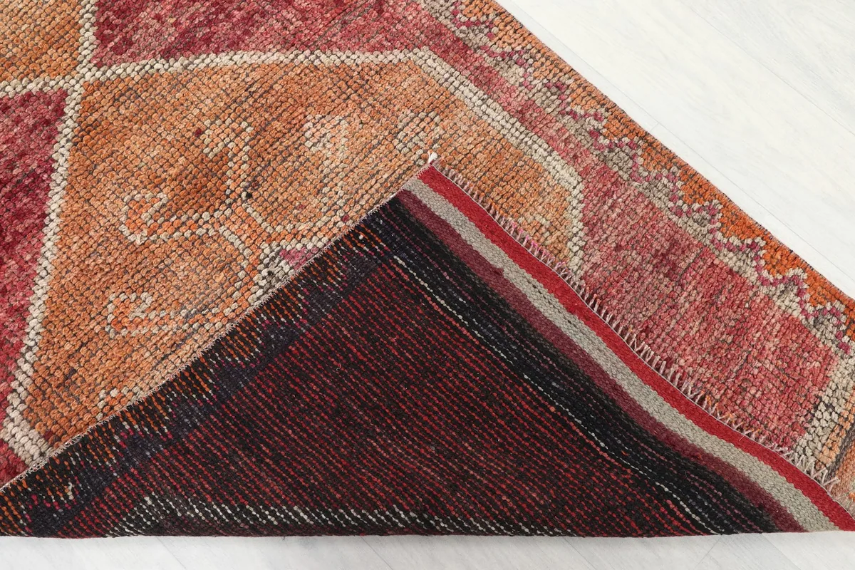 Corner of the runner rug flipped to show the cotton foundation and knotting