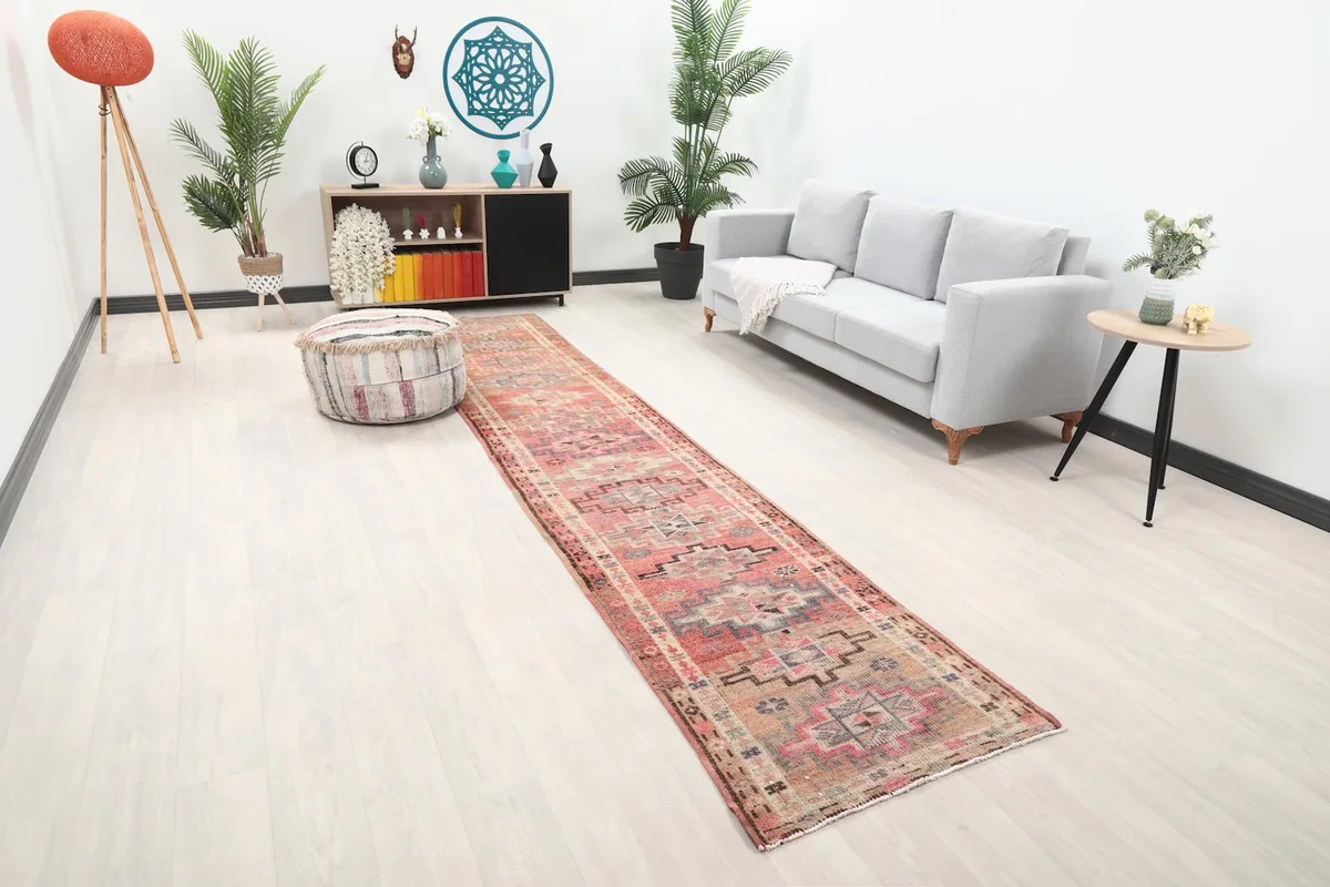 Angle view of the runner rug in a room, highlighting its faded rose colors and geometric motifs