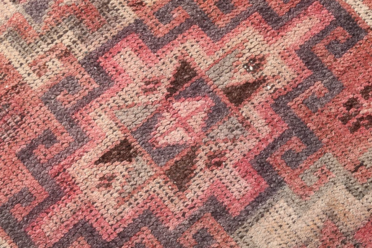 Extreme close-up of the intricate tribal motifs and knotting, showing the low pile and vintage character