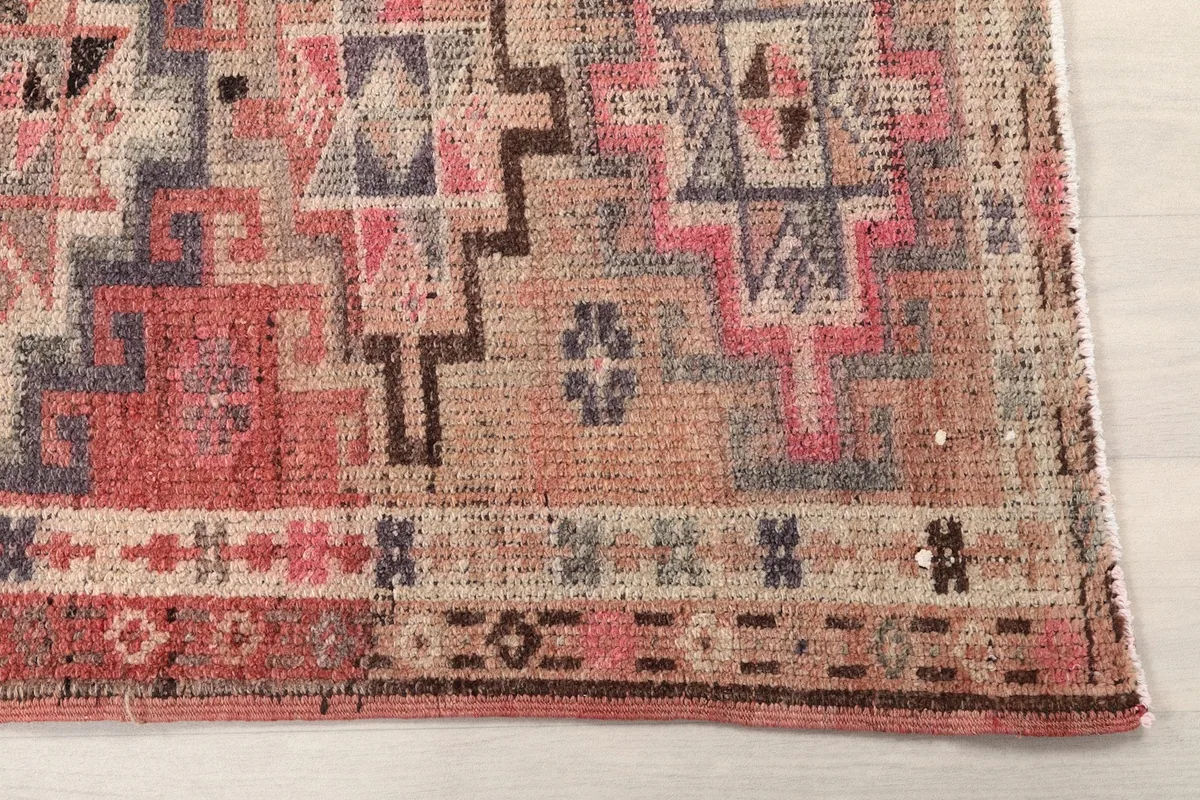 Detailed shot of the rug's border and main field pattern, revealing the hand-knotted wool pile and subtle wear