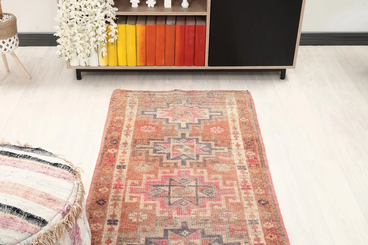 Overhead view of a section of the runner rug in a room, emphasizing its symmetrical design and faded hues
