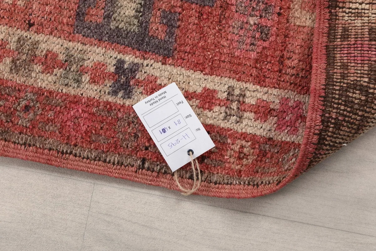 Rug with an attached product tag, showing the quality and origin information alongside the vintage wool pile