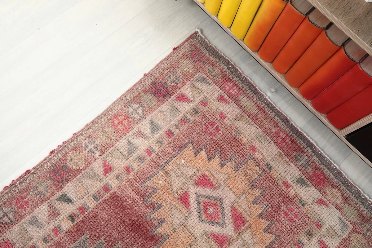 Corner view of the vintage runner rug showcasing its patterns and colors next to a cabinet.